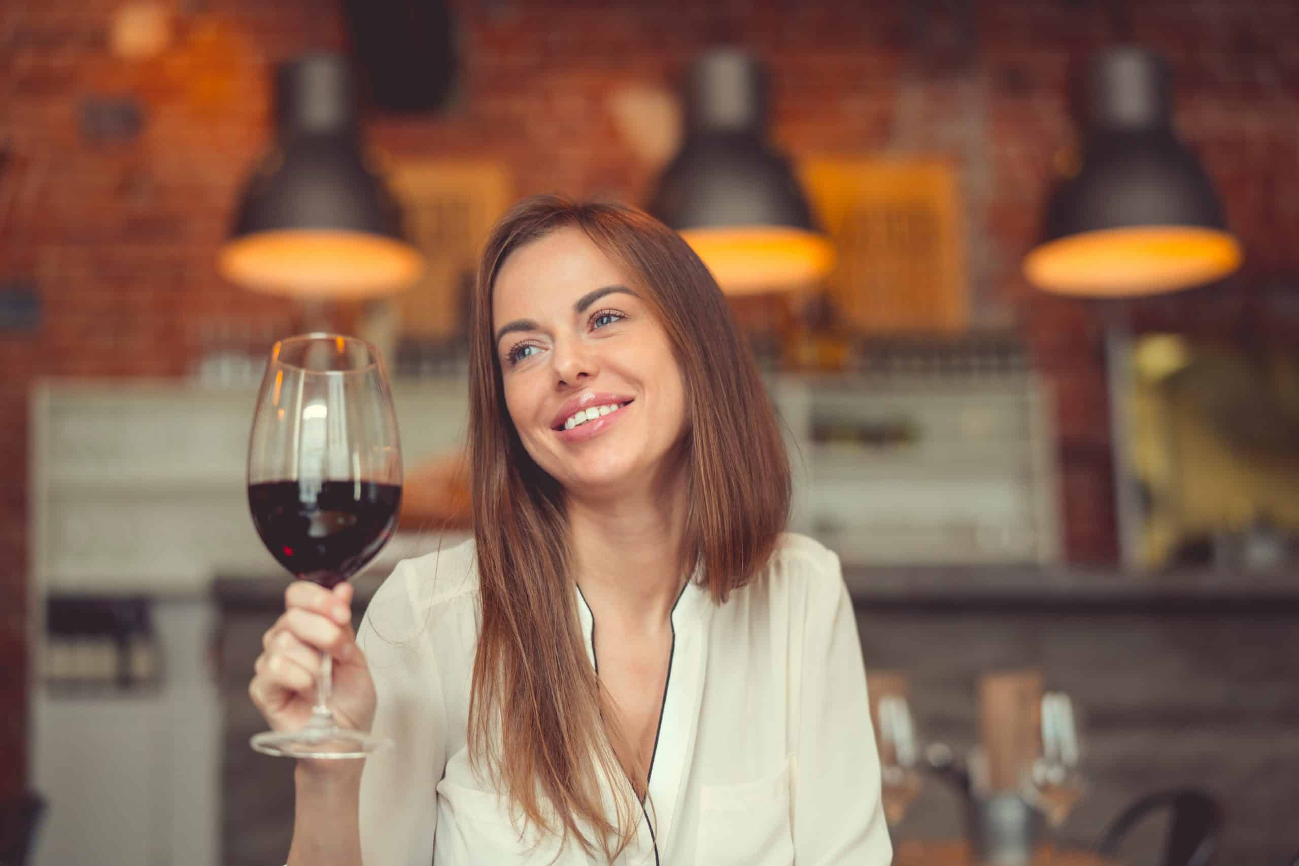 Smiling girl with a glass of red wine in a restaurant